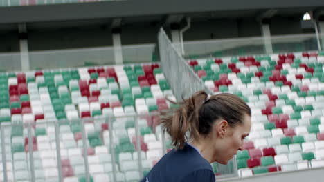 Portrait-of-Caucasian-female-warming-up-before-running-on-an-empty-stadium-track-early-in-the-morning.-Shot-with-anamorphic-lens